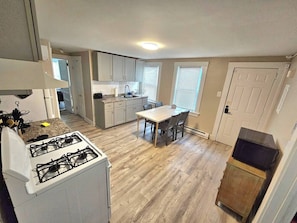 A kitchen with a stove, dining table, and chairs. - Montclair 1st flr Apt/w Porch|Easy Access to NYC (Montclair)