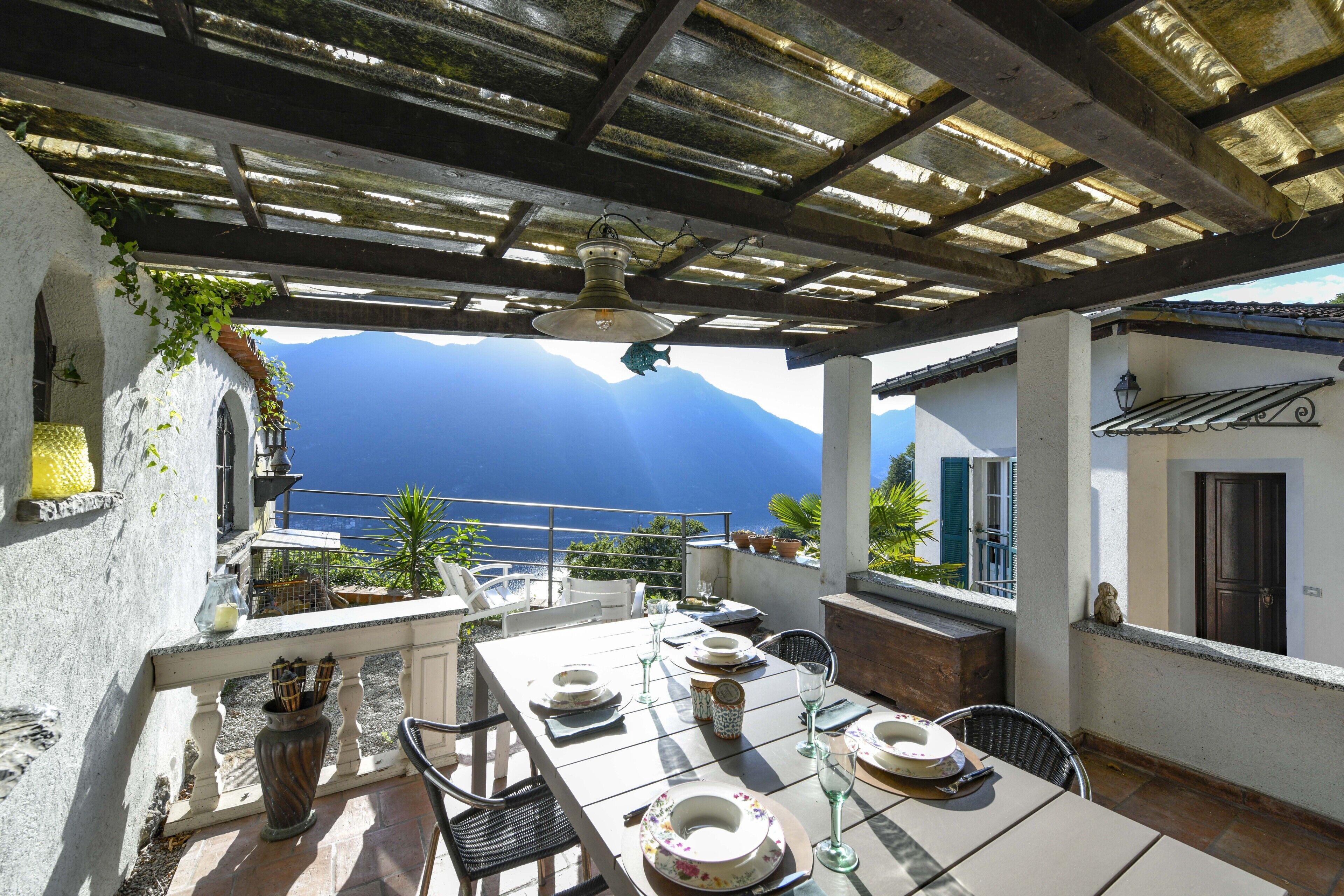 Eine Terrasse mit Esstisch, einer Hängeleuchte und Blick auf das Meer.