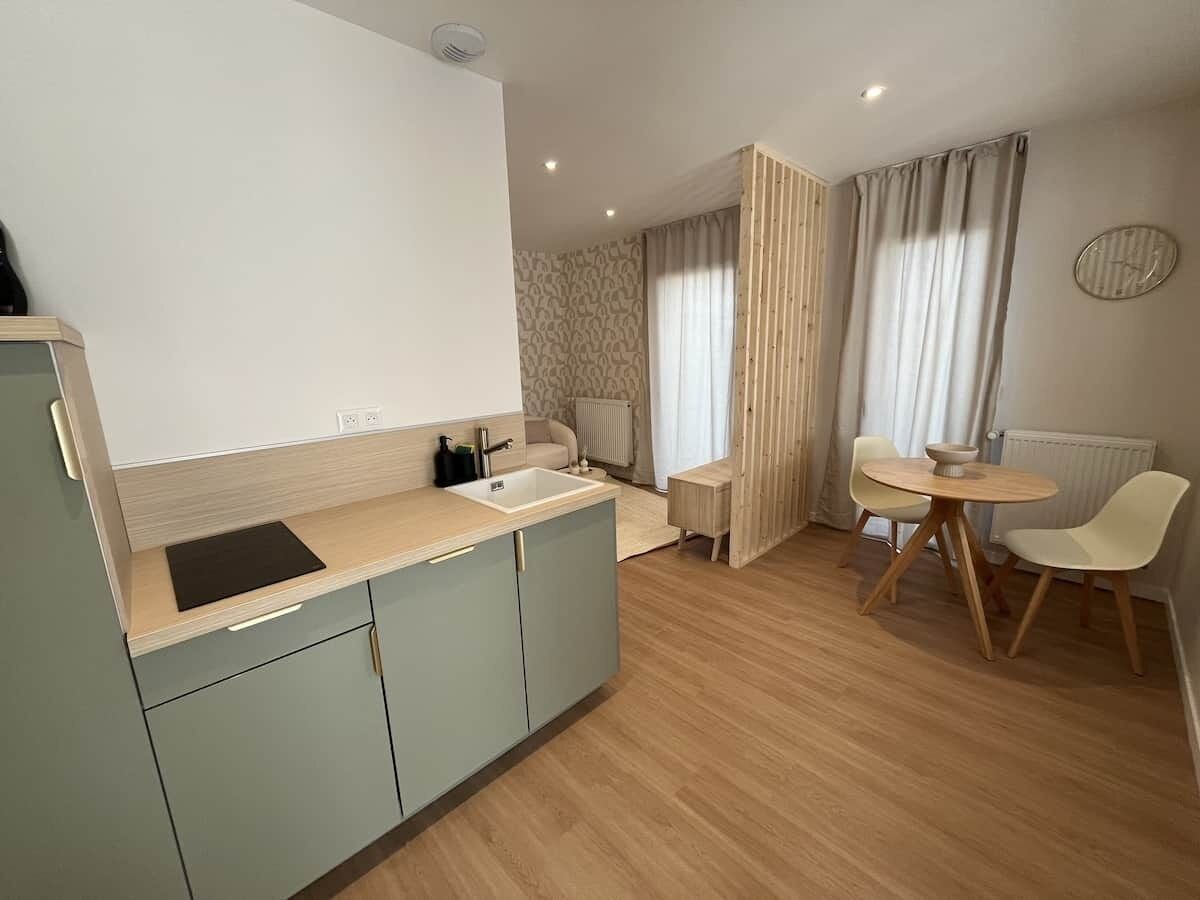 Une cuisine de taille réduite, équipée d’un évier, d’un coin repas avec une table et des chaises, et d’un radiateur.