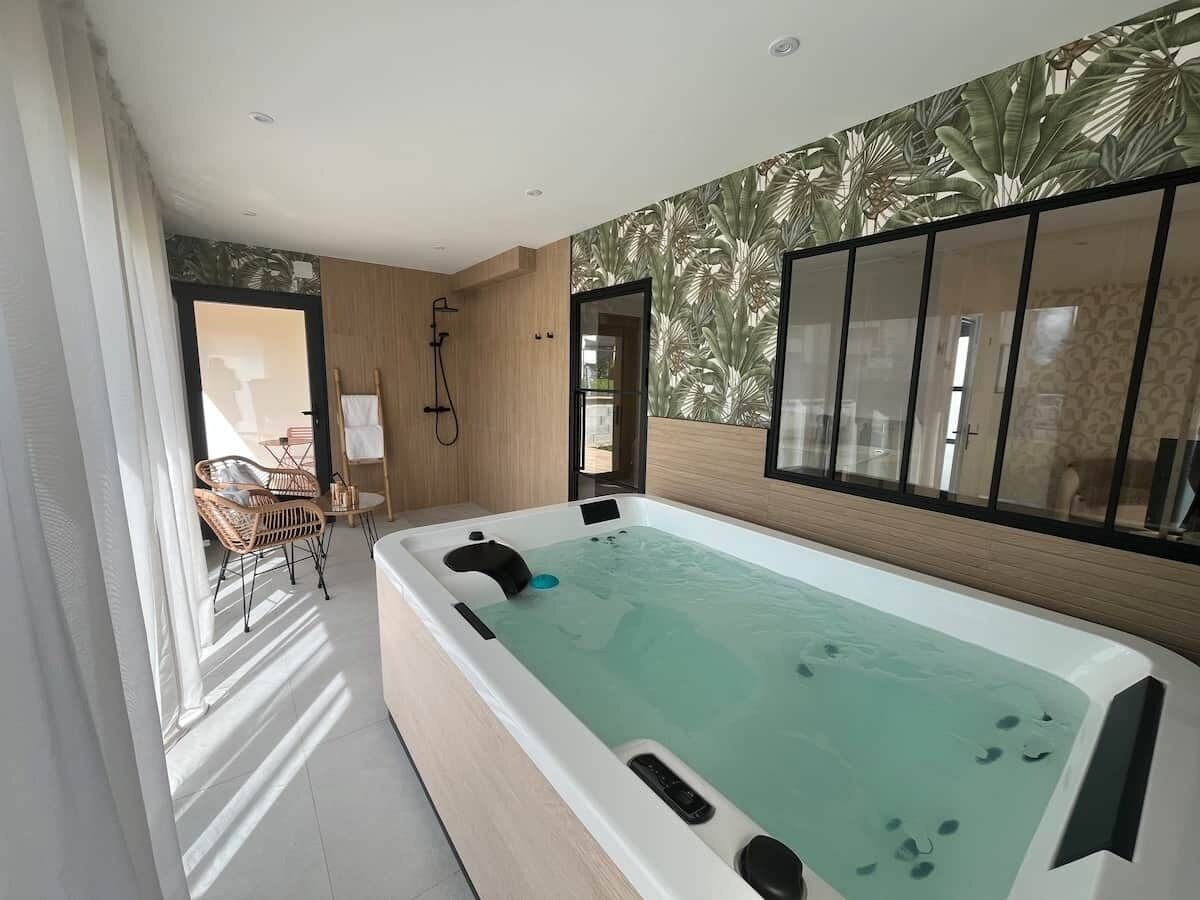 Een moderne badkamer met een groot bad, een douchegedeelte en een zithoek met stoelen.