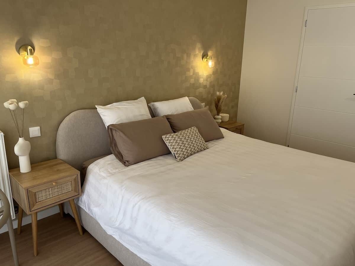 Een slaapkamer met een groot bed, twee nachtkastjes en wandlampen.