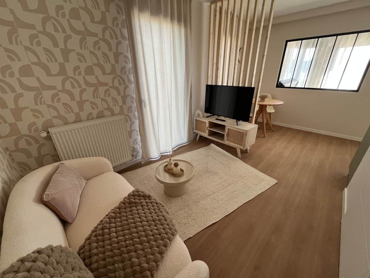 Un salon comprenant un canapé, une table basse, un téléviseur et une petite table avec une chaise.