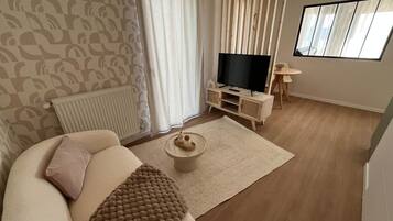 Un salon comprenant un canapé, une table basse, un téléviseur et une petite table avec une chaise.