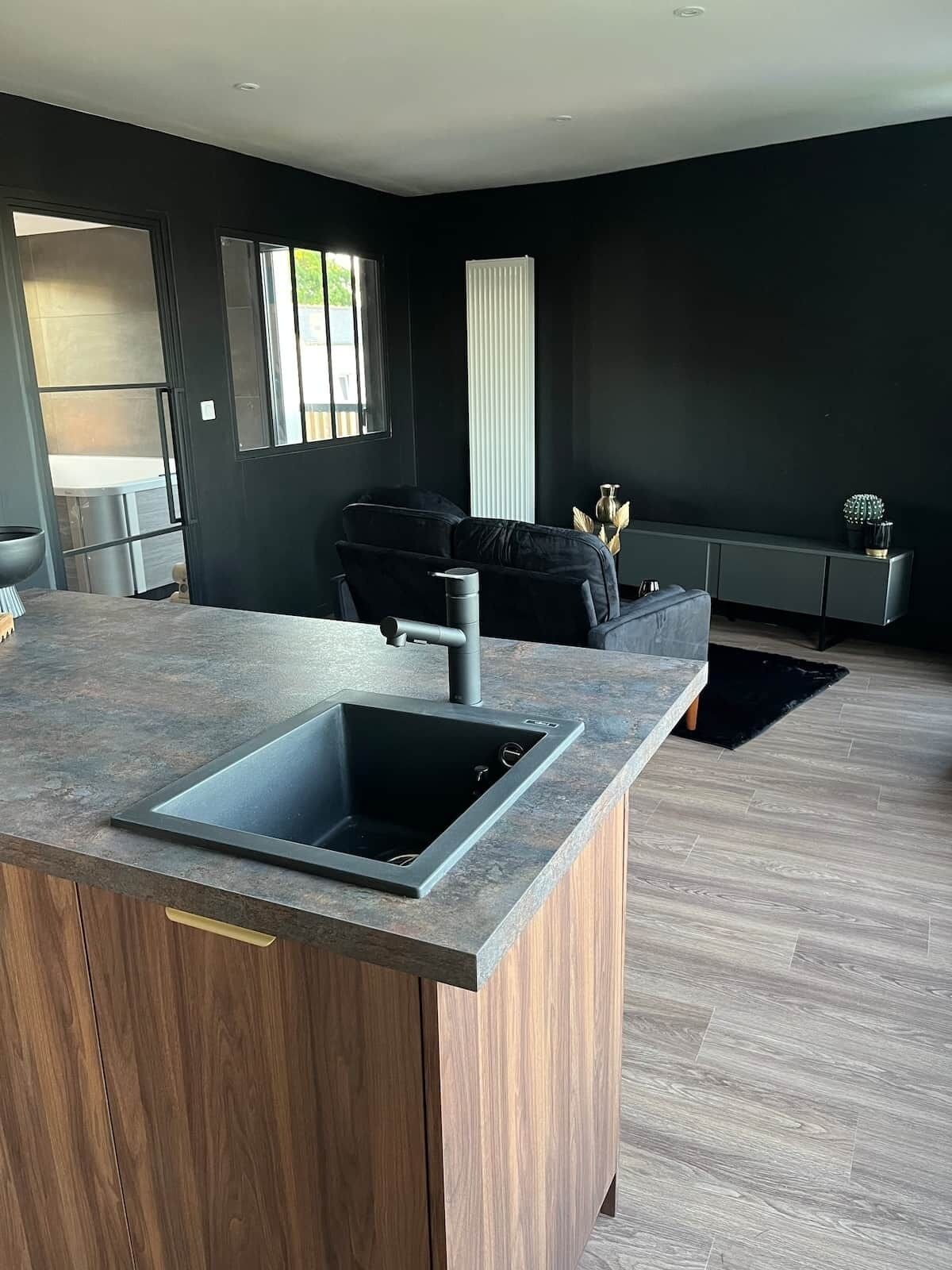 Una cocina moderna con un lavamanos integrado, paredes oscuras y un armario de madera.