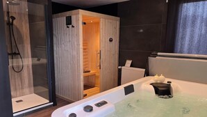 Moderni kylpyhuone, jossa on poreallas, suihkukaappi ja puinen sauna.