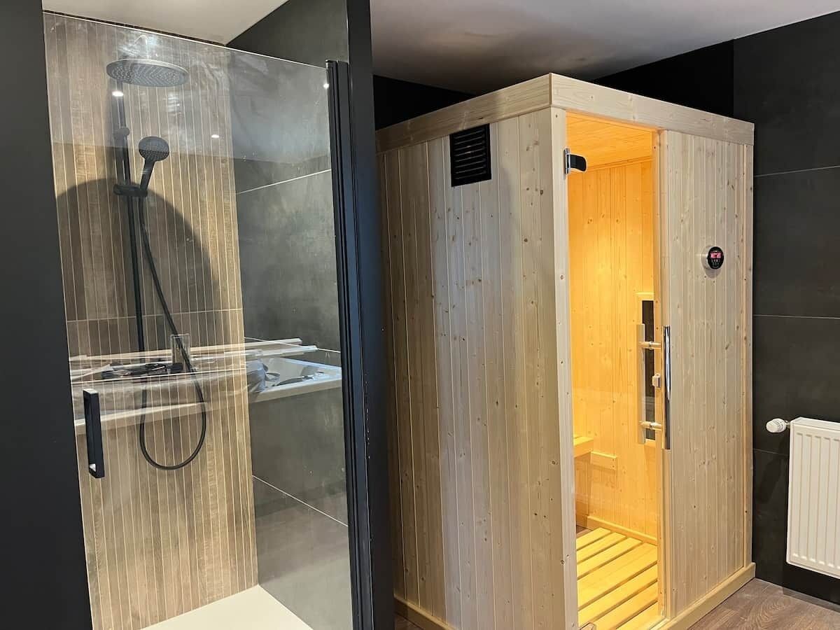Un baño moderno con cabina de ducha de vidrio y sauna de madera.