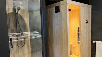 Un baño moderno con cabina de ducha de vidrio y sauna de madera.