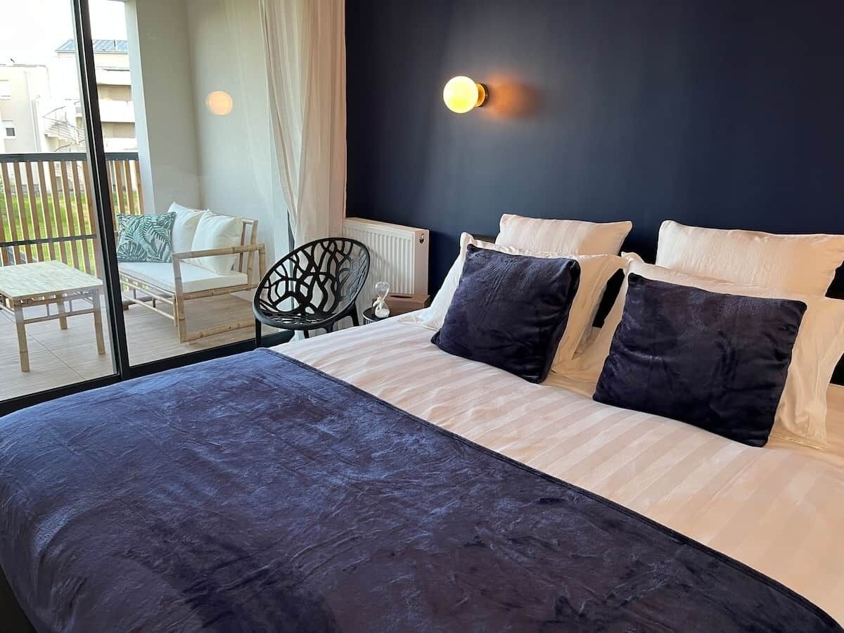Un dormitorio con una cama grande, una silla y vistas al exterior.