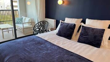Un dormitorio con una cama grande, una silla y vistas al exterior.