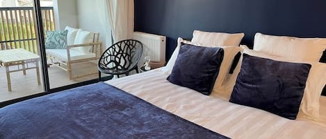 A bedroom with a large bed, a chair, and a view of the outside.