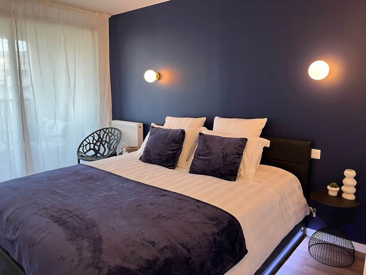 Una camera da letto moderna con un letto grande, pareti scure e due lampade da comodino.