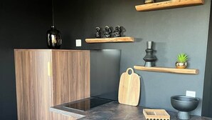 Moderni keittiö, jossa on sisäänrakennettu liesi, pesuallas ja työtaso, jonka päällä on erilaisia esineitä.