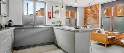 A modern kitchen with grey cabinets, a central island, and a seating area with a sofa and chairs.