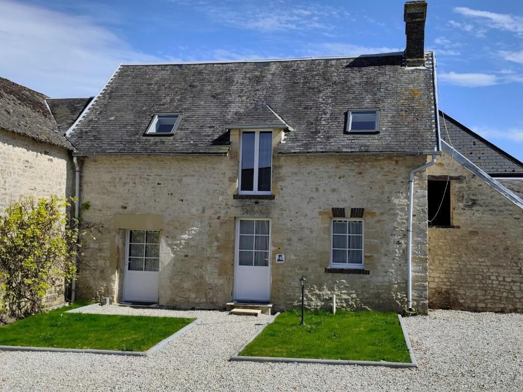 Un bâtiment en pierre avec un toit à pignon, deux portes et une petite fenêtre.