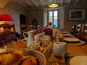 A dining table set for a meal in a room with stone walls and wooden furniture.