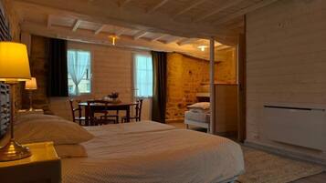 A bedroom with a bed, bedside table, lamp, and a view of a dining area.