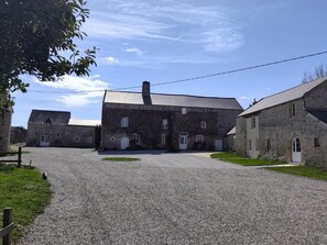 A gravel driveway leading to a stone building with multiple windows and doors.