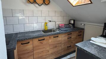 Eine Küche mit Oberlicht, Holzschränken, einer Granitarbeitsplatte und einem gemusterten Teppich.