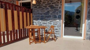 A patio area with a stone wall, wooden table and chairs, and a glass door leading to an outdoor space. - Papaya Suite for 3 guests, located in the nature park, Free parking (Rapallo)
