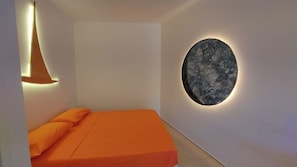 Ein Zimmer mit einem Bett, einer wandmontierten runden Leuchte und einer Wand mit strukturierter Oberfläche.