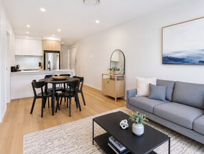 A modern apartment with a dining area, kitchen, living room, and a large window. - Apt 2 - 18 Remembrance Drive - Surfers Paradise (Surfers Paradise)