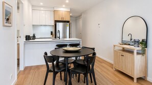 Una cucina moderna con mobili bianchi, un tavolo da pranzo nero con sedie e un armadio in legno con uno specchio.