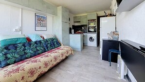 Espai vital reduït amb llit, petita cuina i televisió.