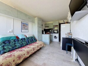 Ein kompakter Wohnraum mit Bett, Küchenzeile und Fernseher.