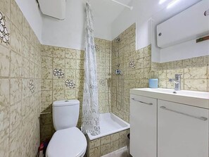 Ein Badezimmer mit Toilette, Dusche, Waschbecken und Schränken.