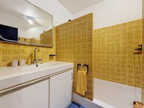 A bathroom with a white sink, mirror, and yellow patterned tiles. - A Pleasant Marina in the DRC (Le Grau-du-Roi)
