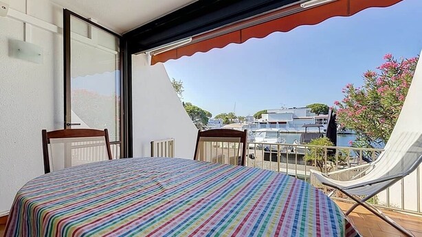 Ein Balkon mit Bett, Stühlen und Blick auf Boote und Gebäude.