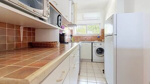 Eine Küche mit Mikrowelle, Waschmaschine und Kühlschrank.