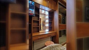 A walk-in closet with wooden shelving, a vanity with a mirror, and a television displaying a movie.