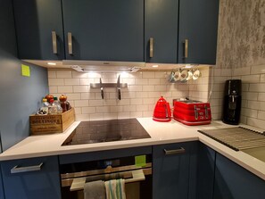 A kitchen with a Siemens induction cooktop, a red toaster, and a coffee maker. - Stylish and Modern 1BDR in Farringdon London (London)
