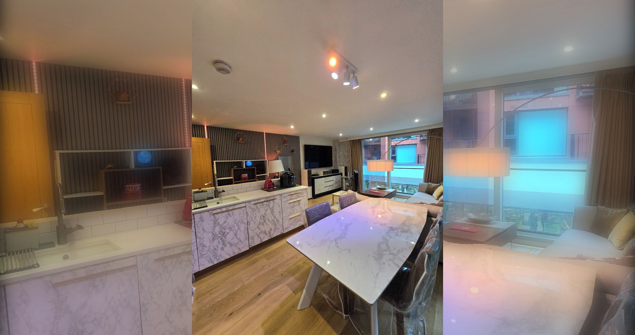 A modern kitchen with marble countertops, a dining area with a large table, and a living space with a TV and large windows.