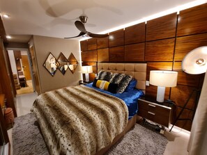 A bedroom with a large bed, a ceiling fan, wooden paneling, and two bedside lamps. - Stylish and Modern 1BDR in Farringdon London (London)