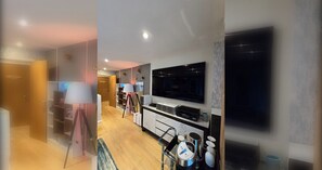 A modern living room with a flat-screen TV mounted on the wall, a coffee table, and a sofa. - Stylish and Modern 1BDR in Farringdon London (London)