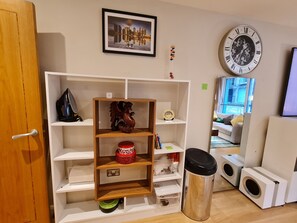 A living room with a bookshelf, a clock, and a window with a view. - Stylish and Modern 1BDR in Farringdon London (London)