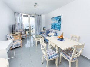 Ein modernes Wohnzimmer mit Sofa, Esstisch, Stühlen und Fernseher.