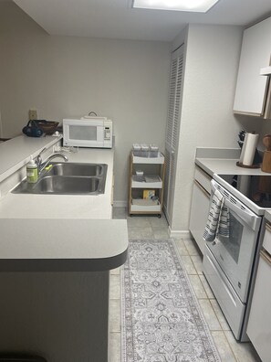 A compact kitchen with a microwave, sink, and oven. - Beautiful 2-bedroom centrally located Salt Pond Condo in sunny Key West (Key West)