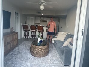 A living room with a sofa, a coffee table, and a dining area with chairs and a kitchen in the background. - Beautiful 2-bedroom centrally located Salt Pond Condo in sunny Key West (Key West)