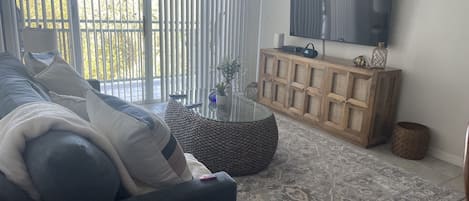 A living room with a sofa, a coffee table, a TV, and a wooden cabinet.