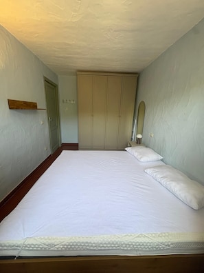 Une chambre avec un grand lit, une armoire et un miroir au mur.