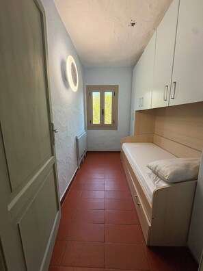 A compact room with a bed, a window, a door, and a wall-mounted fan. - Porto Rotondo Costa Smeralda Sea-view apartment, residence with pool, tennis (Porto Rotondo)