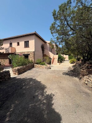 A two-story building with a stone facade, a stone staircase, and a gravel driveway. - Porto Rotondo Costa Smeralda Sea-view apartment, residence with pool, tennis (Porto Rotondo)