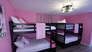 Una habitación con literas, una pared rosa y una lámpara en el techo.