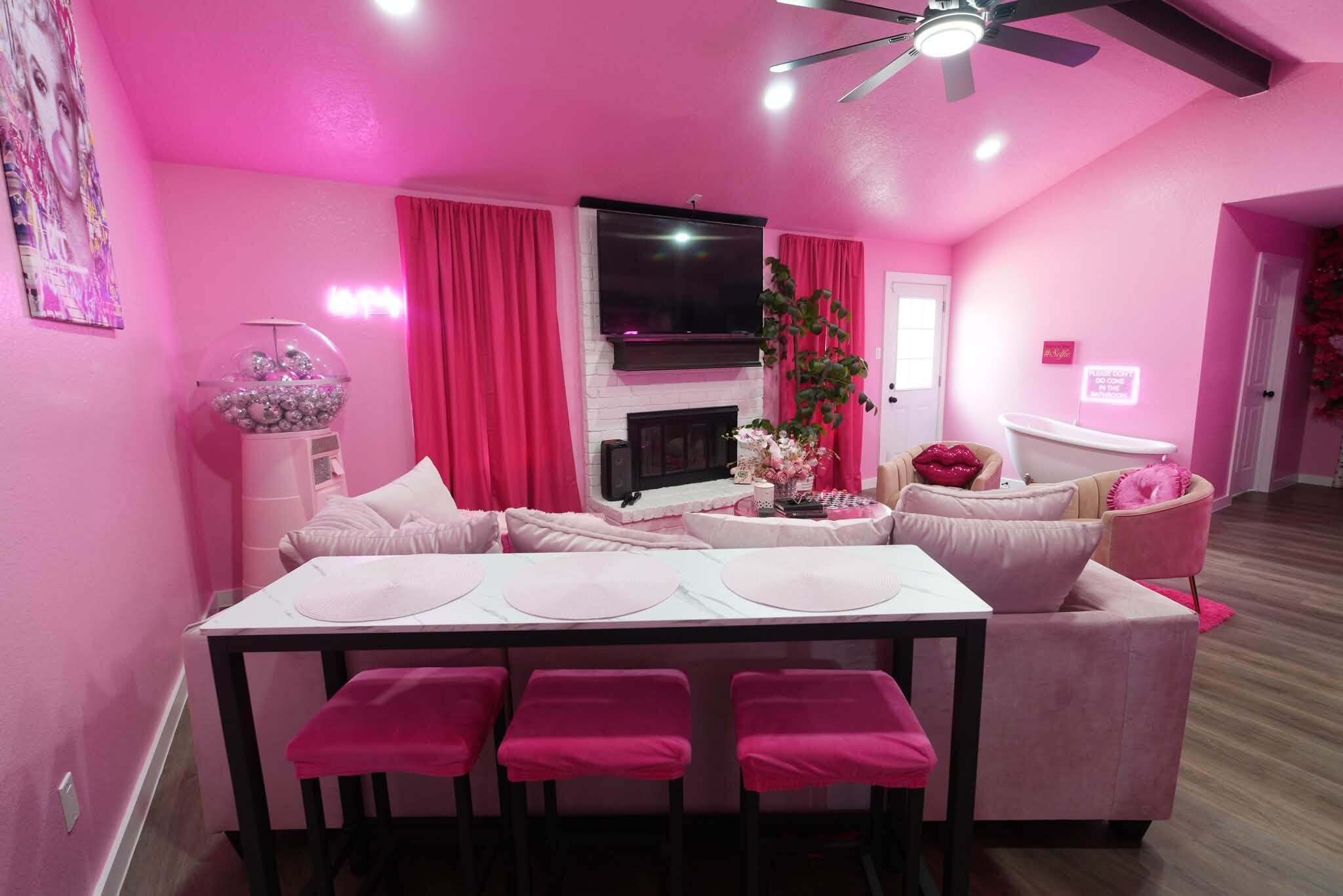 A pink-themed living room with a dining table, sofas, and a television.