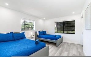 Un dormitorio moderno con dos camas, ventanas amplias y un diseño minimalista.