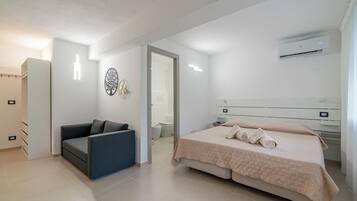 Un dormitorio moderno con cama, sofá, armario y aire acondicionado.