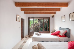 A bedroom with two beds, a wooden ceiling, a stone staircase outside, and a view of greenery. - Holiday Home 'Can Carabá' with Mountain Views, Private Pool, and Wi-Fi (Sóller)
